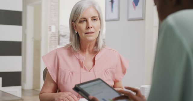Senior woman consulting with a doctor who is using a digital tablet. Ideal for healthcare promotion, medical advice services, patient and doctor interactions, and technology in healthcare advertisements.