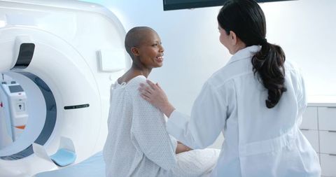Female patient receiving CT scan while clinician offering reassuring support and guidance