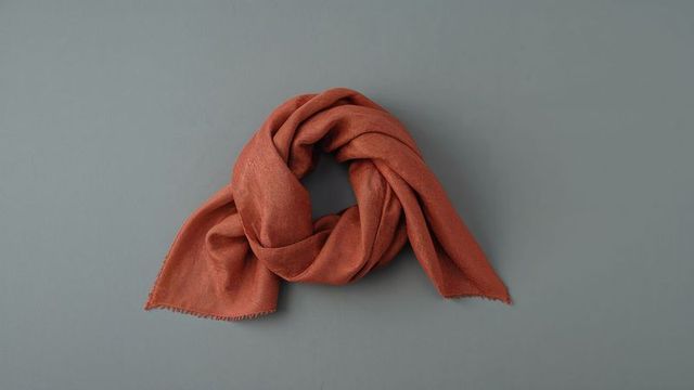 Rust-colored scarf display on gray-blue surface