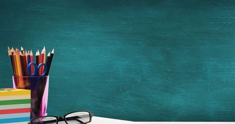 Creative workspace with colorful pencils and clean blue chalkboard