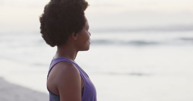 Woman stands by the ocean during sunset, meditating in serene atmosphere. Ideal for projects on meditation, mental health, relaxation and travel. Can be used in blogs, advertisements, wellness programs or inspirational quotes.