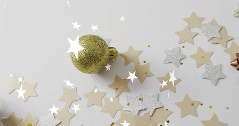 Gold glitter bauble with beige and silver star confetti on white for minimal holiday decor