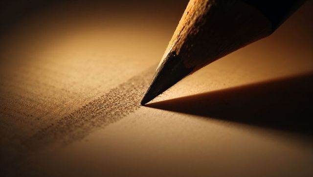Sharp pencil tip shading textured paper in warm light macro closeup for creative concept
