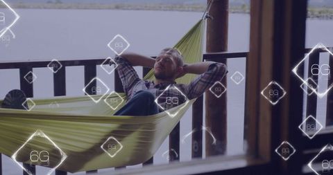 Relaxed man exploring 6g technology in a lakeside hammock