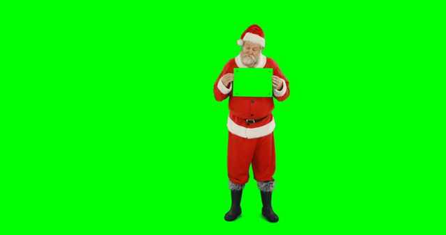 Happy father christmas holding green screen flat screen device on green screen background. Christmas, santa claus, celebration, technology, communication, digital interface and tradition, unaltered.