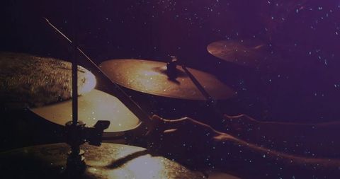 Playing cymbals close-up: drummer hands and drumsticks in low-light stage rehearsal