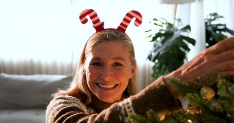 Mature woman decorating christmas tree with antler headband