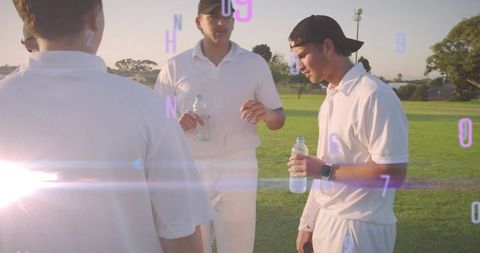 Cricket players gathering during golden hour holding water bottles with lens flare