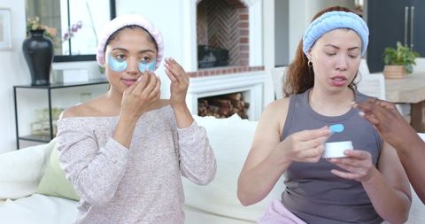 Friends applying under-eye patches and moisturizer during at-home spa and self-care