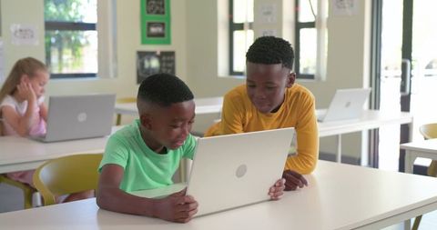African American Boys Collaborating on Laptop Learning Skills and Teamwork in Bright Classroom