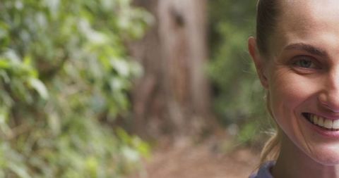 Half-face smiling woman on forest trail with generous left copy space for branding