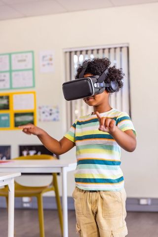 African american boy exploring vr in classroom wearing headset and headphones