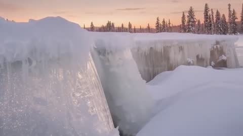 Sunset frozen waterfall sparkling, ice column reflecting golden glow in snowy twilight video
