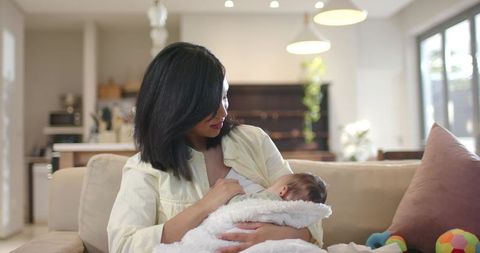 Mother Breastfeeding Infant on Cozy Sofa in Sunlit Living Room