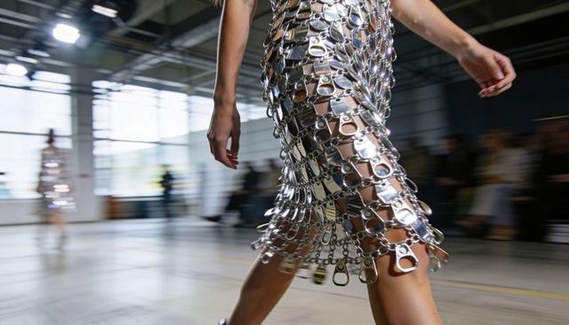 Model striding in recycled pull-tab metallic dress at industrial runway fashion show