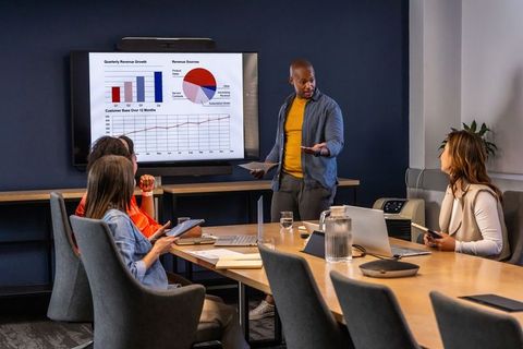African american man presenting growth charts to diverse team in modern conference room