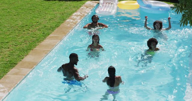 A diverse group of friends enjoying a sunny day in a pool, swimming and laughing together. Ideal for concepts related to summer fun, outdoor activities, relaxation, and social gatherings. Can be used for promoting summer events, travel destinations, pool safety, or lifestyle magazines.