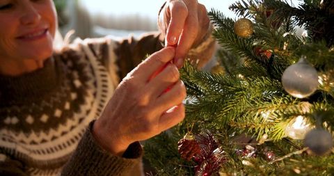 Woman Decorating Christmas Tree with Pinecone Ornament
