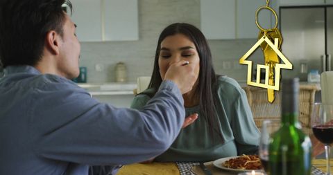 Happy couple enjoying meal in new home with golden key symbol