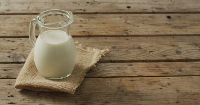 Image of glass jug of milk on wooden background. dairy products and healthy organic nutrition.
