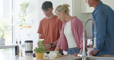 Multigenerational Family Preparing Green Smoothie Together in Sunlit Modern Kitchen