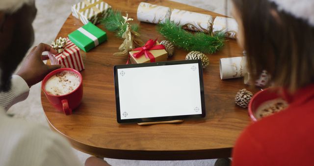 Image of happy diverse couple making christmas image call on tablet at home, copy space on screen. Christmas, celebration, communication, happiness and inclusivity concept.