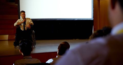 Disabled Businessman on Wheelchair Speaking in Seminar Auditorium
