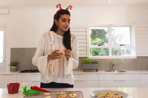 Festive Asian Woman Decorating Christmas Cookies in Kitchen