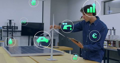 Engineer analyzing wind turbine and solar panel prototype in laboratory
