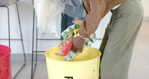 African American woman and child placing egg cartons into yellow recycling bin