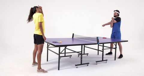 Diverse table tennis partners warming up near purple ping-pong table