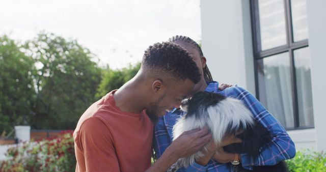 Happy african american couple petting dog in backyard. Lifestyle, relationship, spending free time together concept.