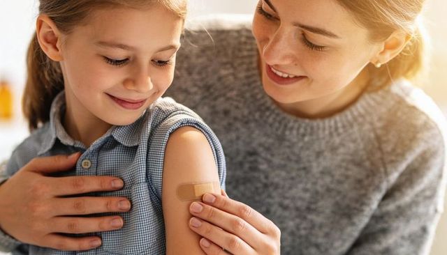 Mother applying bandage to smiling child's upper arm showing care and reassurance