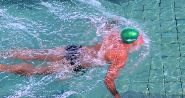 Swimmer practicing strokes in clear blue pool, showcasing fitness and dedication to sport. Ideal for use in promoting aquatic sports, health and fitness programs, and athletic training facilities.