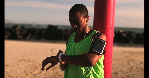 Young African American Male Jogger Using Smartwatch on Sunny Beach - Download Free Stock Images Pikwizard.com