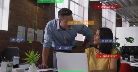 Colleagues collaborating over laptop in modern loft office with social media notifications