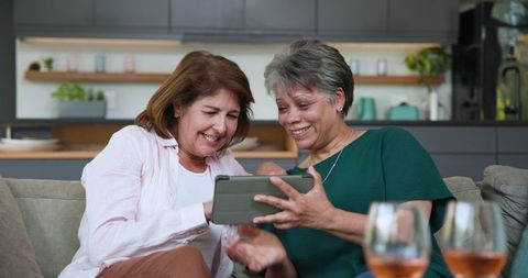 Senior Mother and Daughter Bonding Over Tablet on Sofa