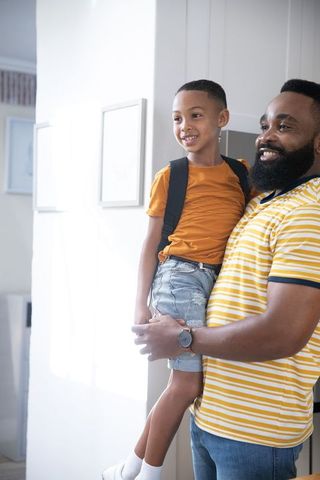 Caring African American Father Bonding with Son in Bright Hallway