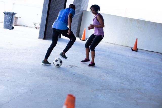 African american man and woman playing football in empty urban building. urban fitness healthy lifetyle.