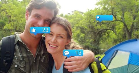 Cheerful couple camping with hiking gear and social media icons