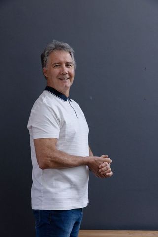 Confident mature man in casual wear standing against gray wall