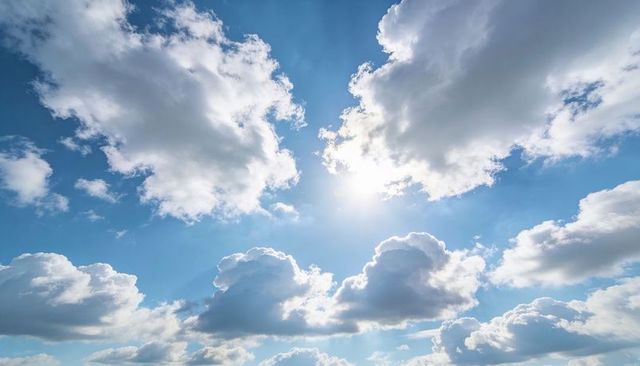 Sunburst Through Billowing Cumulus Clouds Over Bright Blue Sky, Backlit Rays and Flare