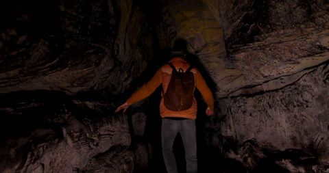 Adventurous man exploring dark natural cave