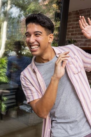 Cheerful Man Gesturing Playfully Near Glass Door at Home