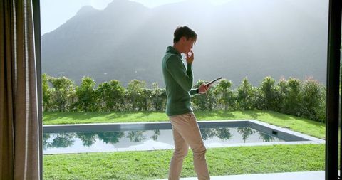 Man with Tablet in Modern Home by Tranquil Pool View