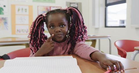 Child drawing with marker in classroom with expression of thought