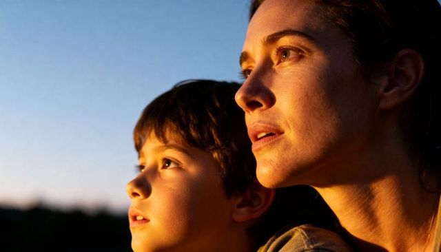 Mother and son gazing at sunset bathed in golden light intimate outdoor family portrait