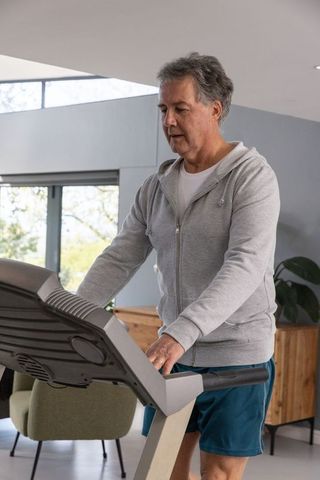 Man adjusting treadmill settings in modern home gym