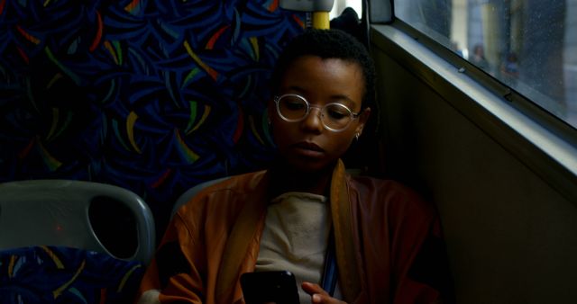 Young woman with glasses sitting on bus using smartphone - Download Free Stock Images Pikwizard.com