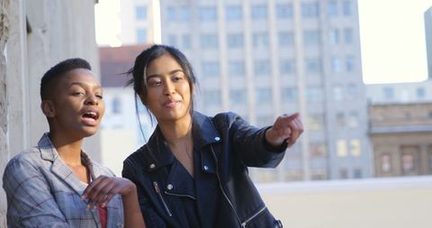 Two friends engaged watching urban view with copy space